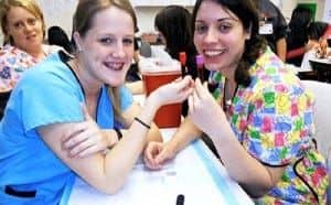 Two women in scrubs holding a vial of blood